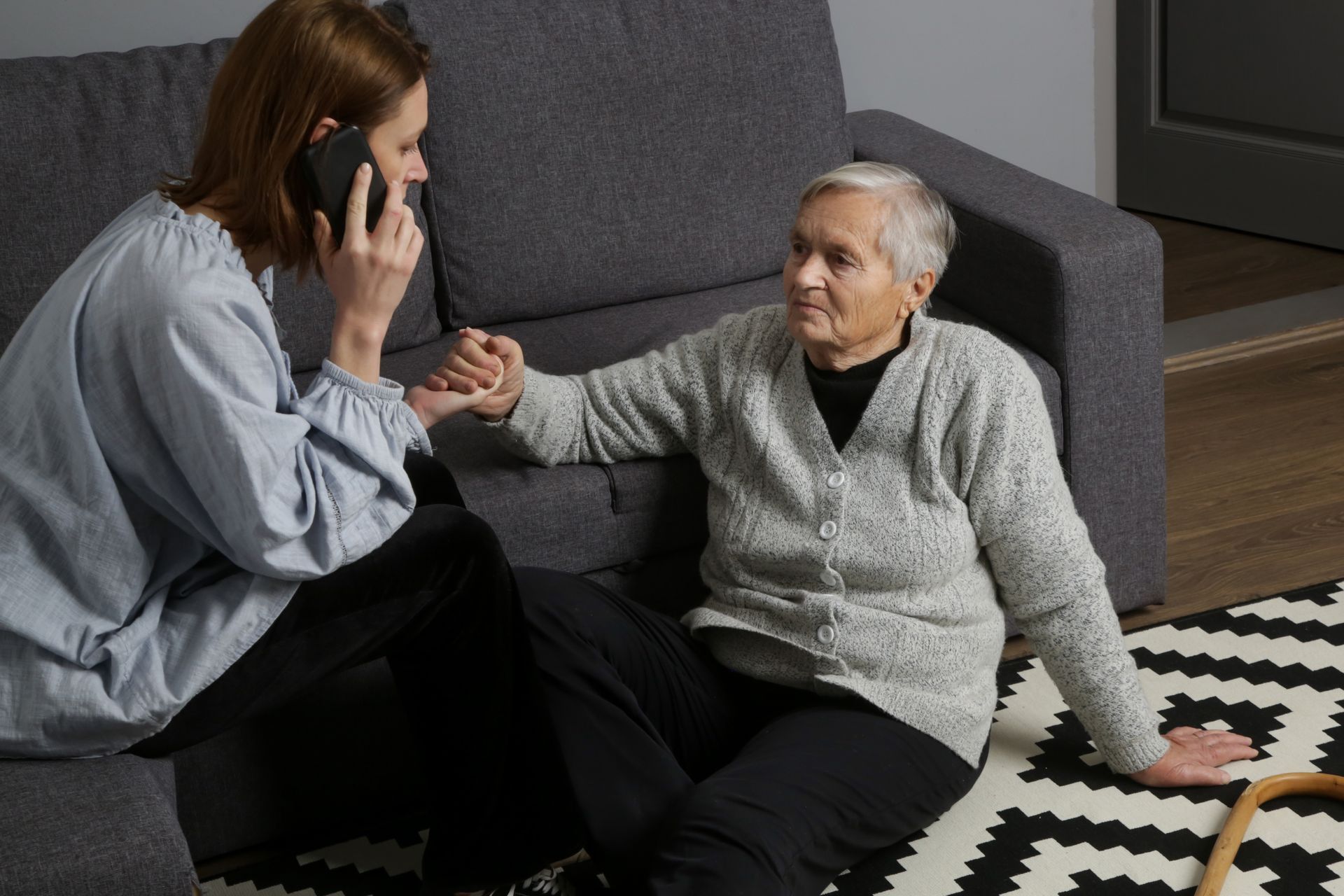 Échange téléphonique entre une aidante et une personne âgée assise sur un canapé