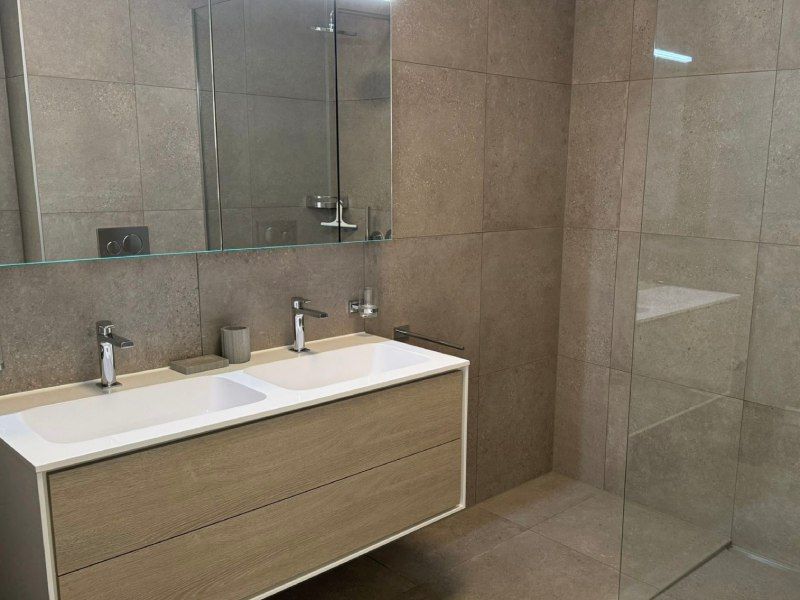 Une salle de bain avec deux vasques et une douche à l'italienne.