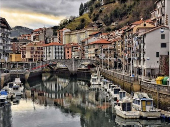Una fila de barcos están atracados en un puerto frente a una ciudad.