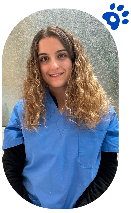 Una mujer con bata de laboratorio y gafas sonríe a la cámara.