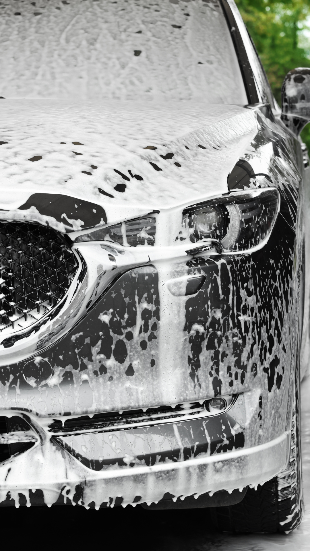 Voiture recouverte de mousse blanche savonneuse lors d'un lavage.