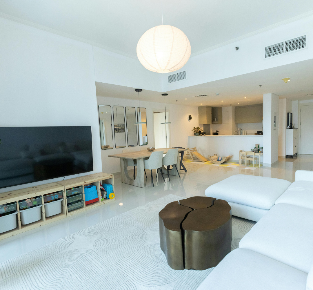 Séjour avec canapé blanc, TV, coin repas et décoration moderne.