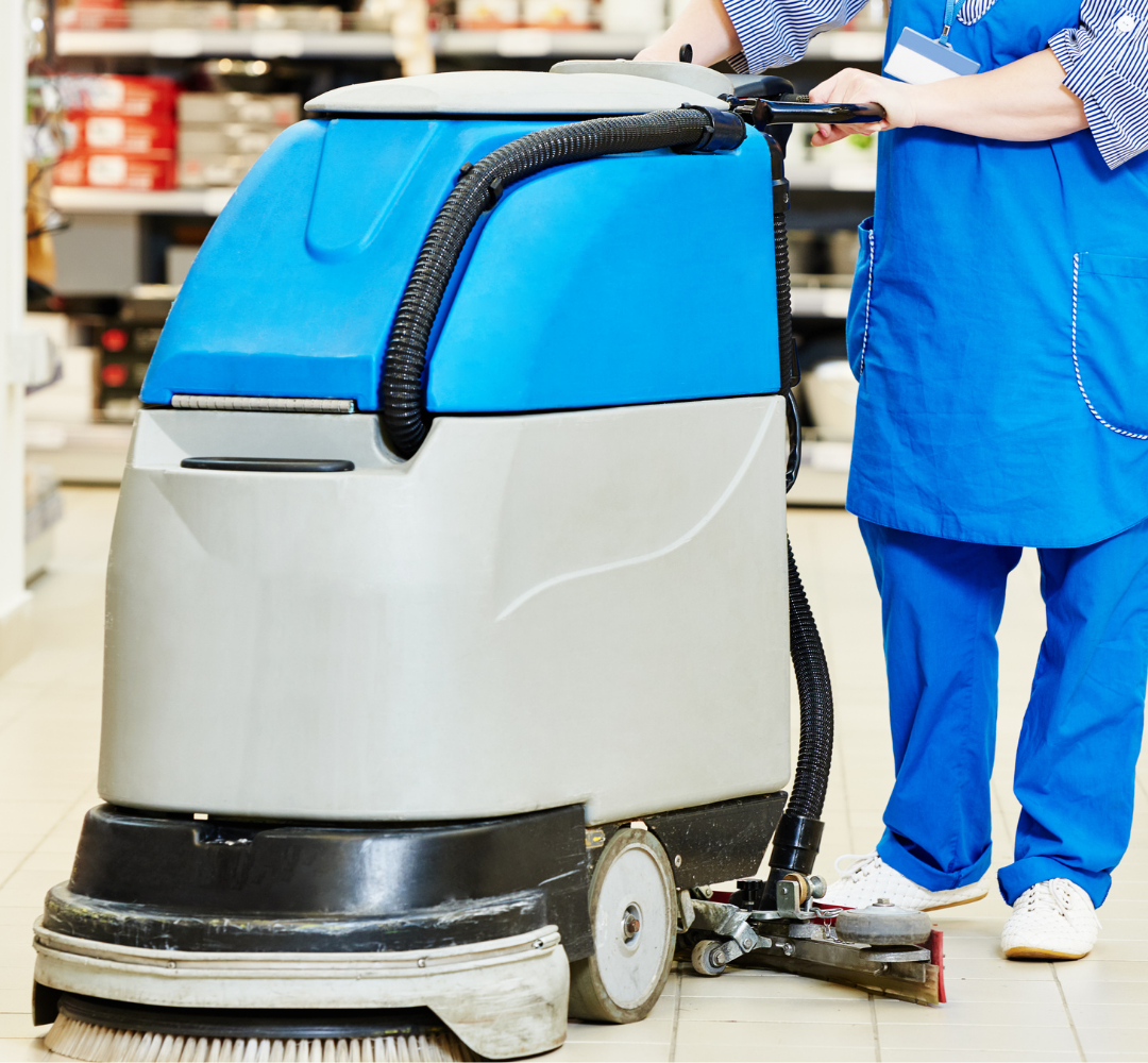 Une personne en tenue bleue utilise une machine de nettoyage de sol bleue et grise dans un magasin.