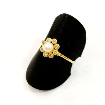 Un anillo de oro con una perla y diamantes en un soporte de anillo negro.