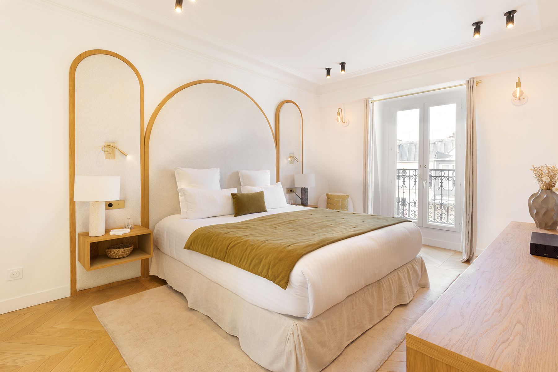 Bright minimalist bedroom with exposed wooden beams, white bed linens, and a large window with curtains