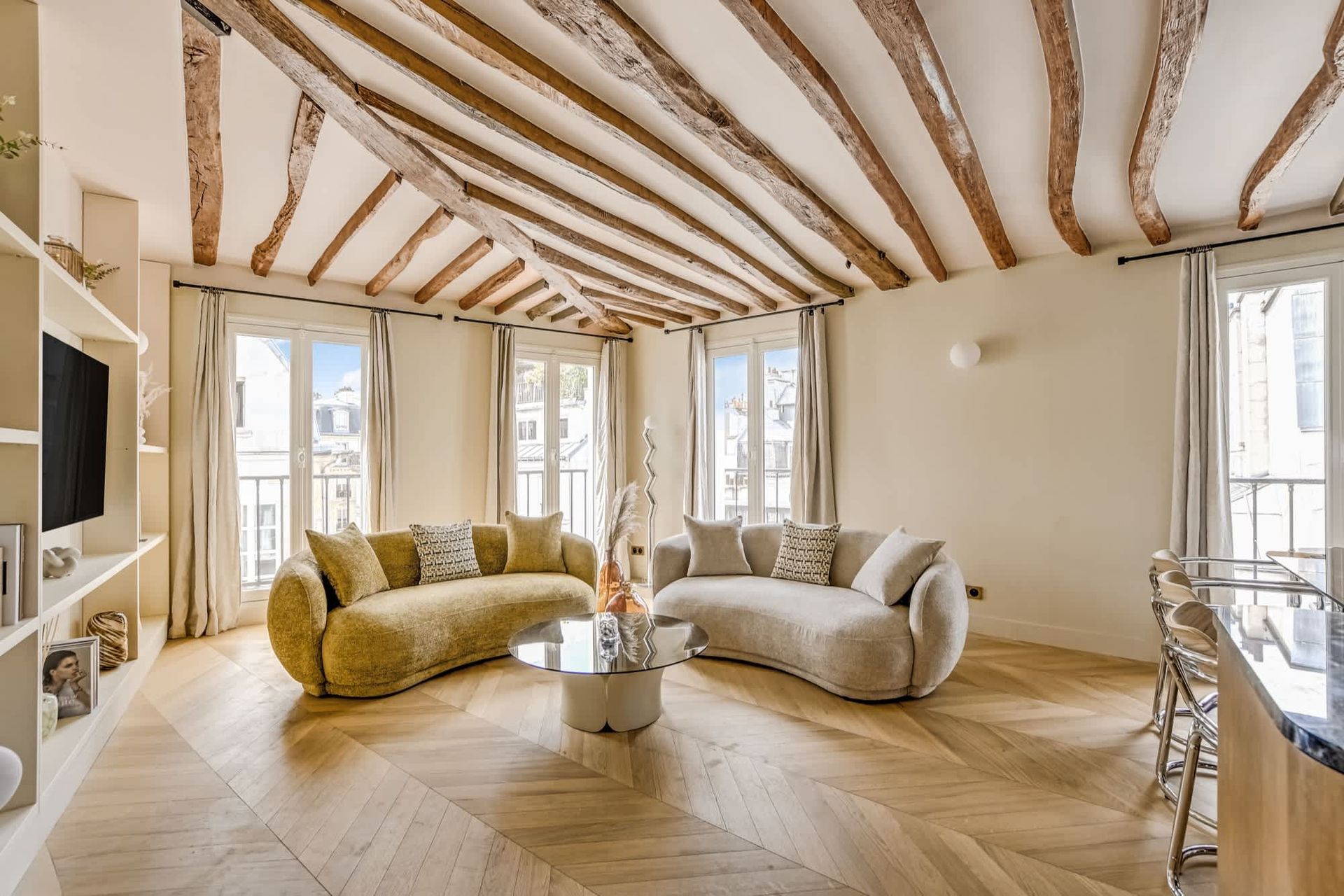 Bright modern living room with exposed beams, curved sofas, and large windows
