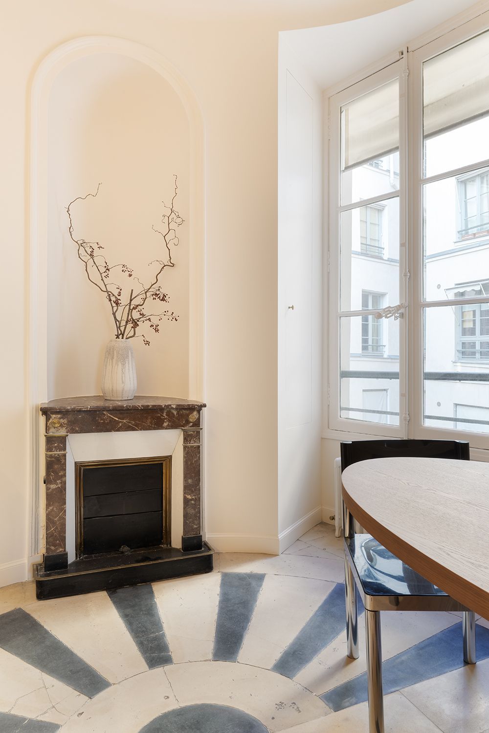 Elegant room with marble fireplace, arched alcove, and large windows beside a round table