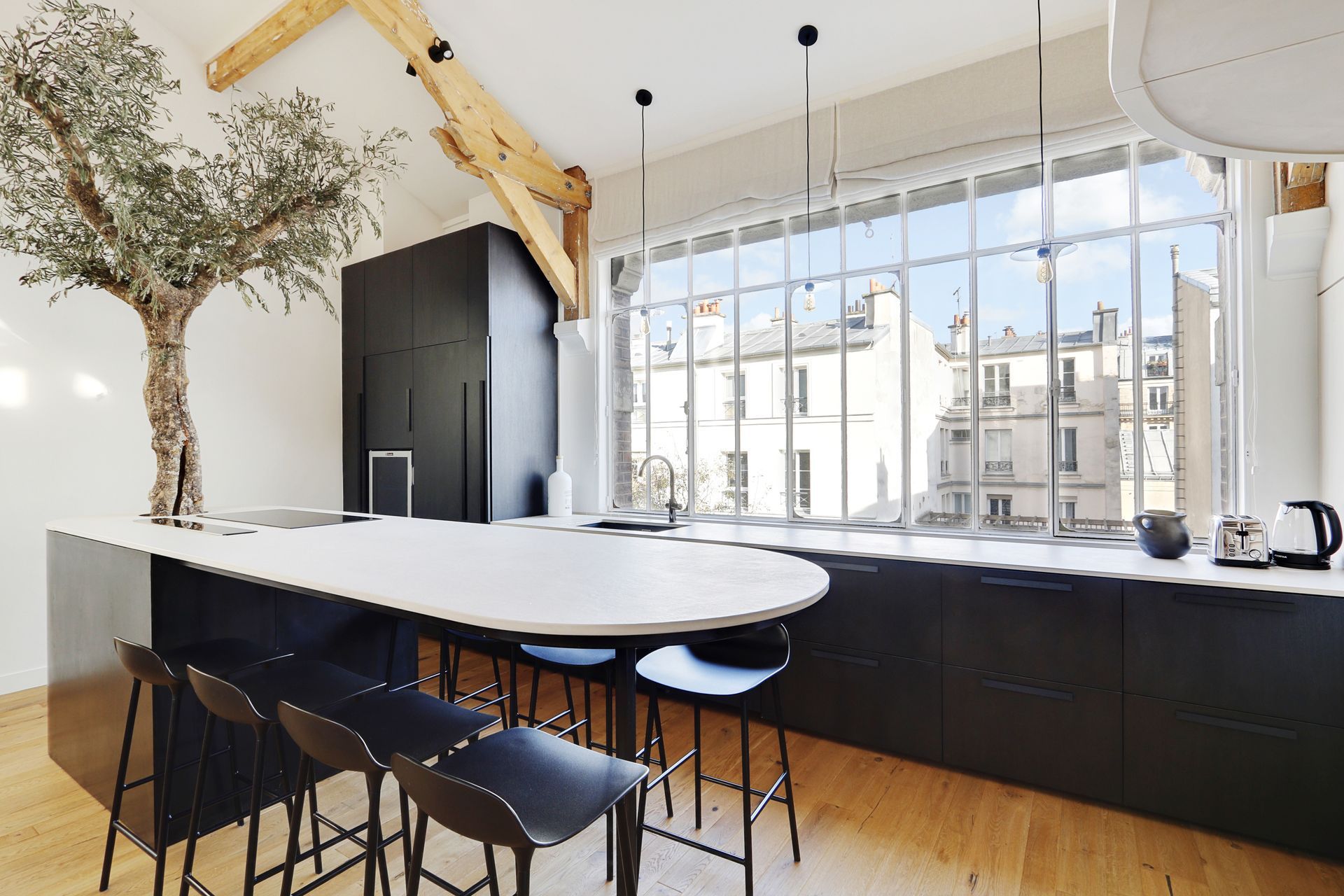 Bright, modern living-dining room with white furniture, wood cabinets, and a round table by sliding doors