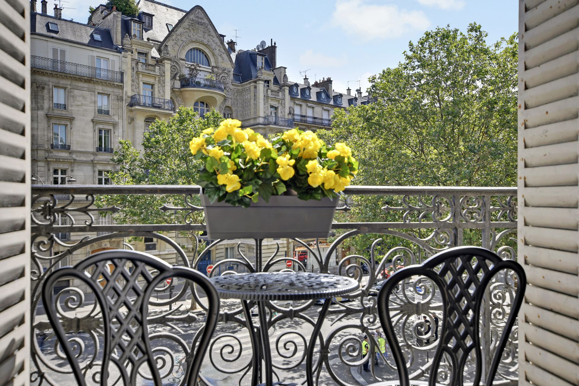 Balcony café table with yellow flowers overlooking a Parisian street and historic buildings