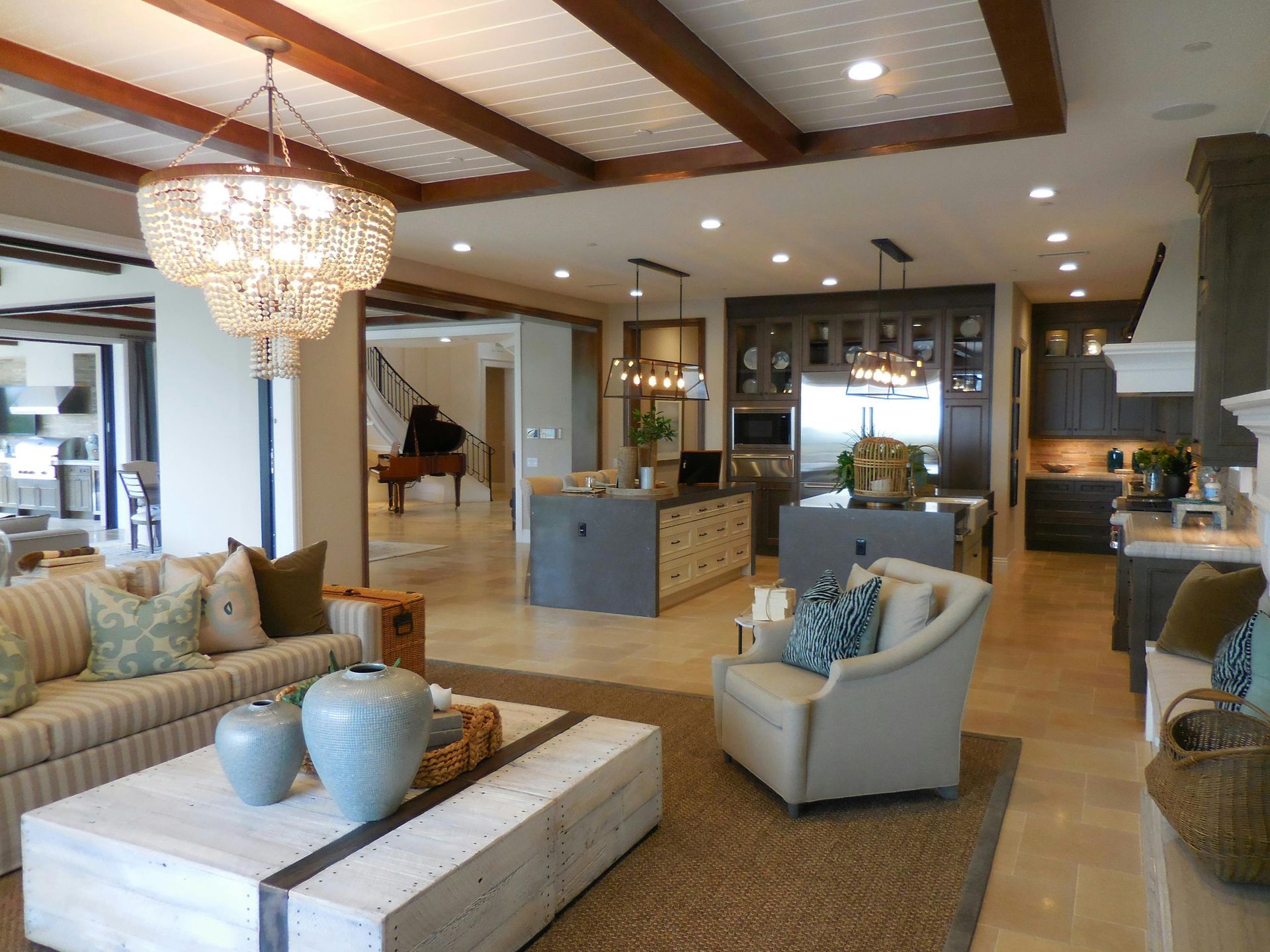 Bright modern living room with sofas, armchair, chandelier, and open kitchen in the background