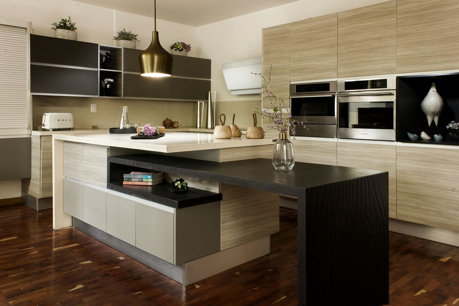 Modern kitchen with dark island, beige cabinets, built-in ovens, and hardwood floor