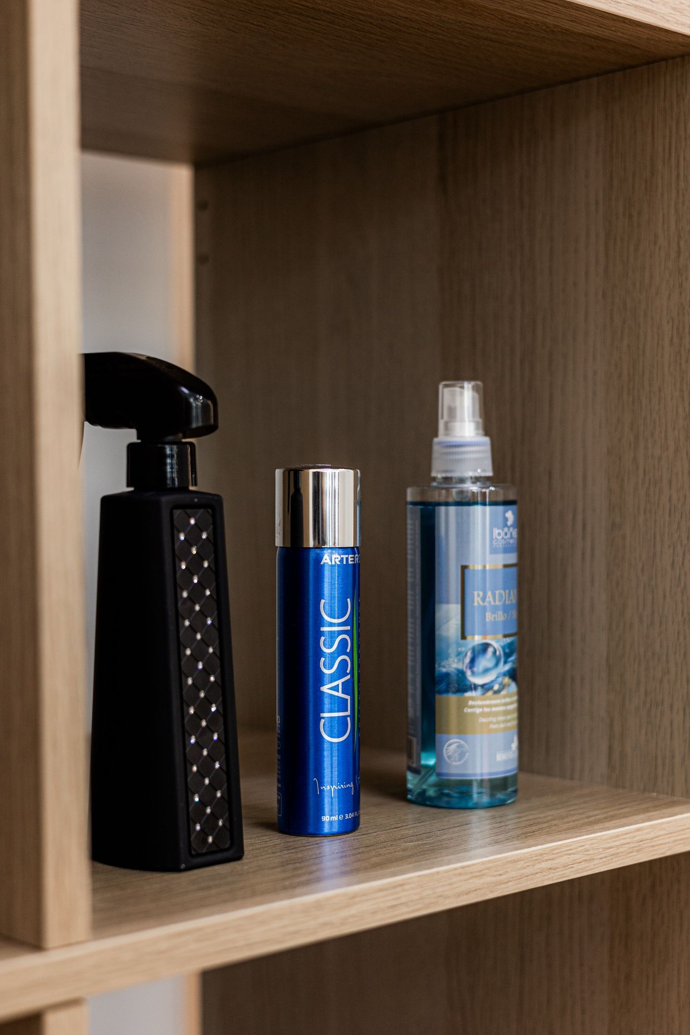 Hay tres frascos de perfume en un estante de madera.