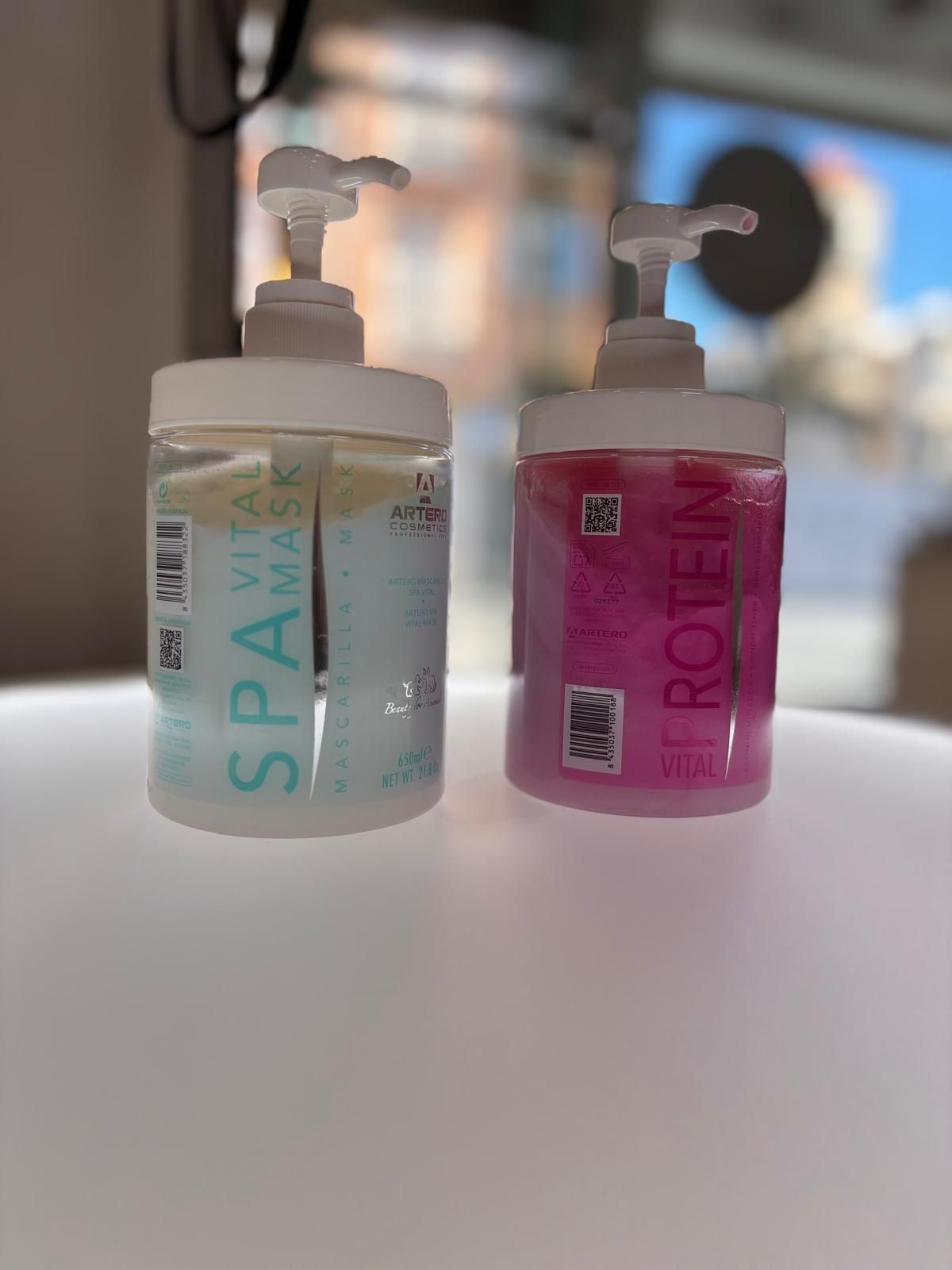 Dos botellas de champú y acondicionador están sobre una mesa.