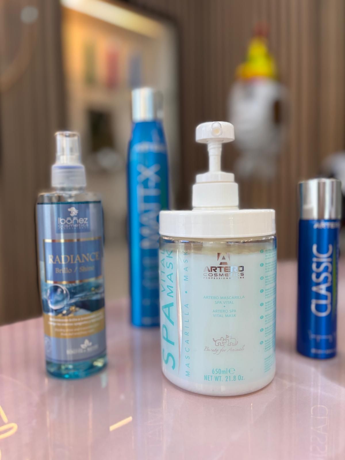 Varias botellas de productos para el cabello se encuentran sobre una mesa rosa.