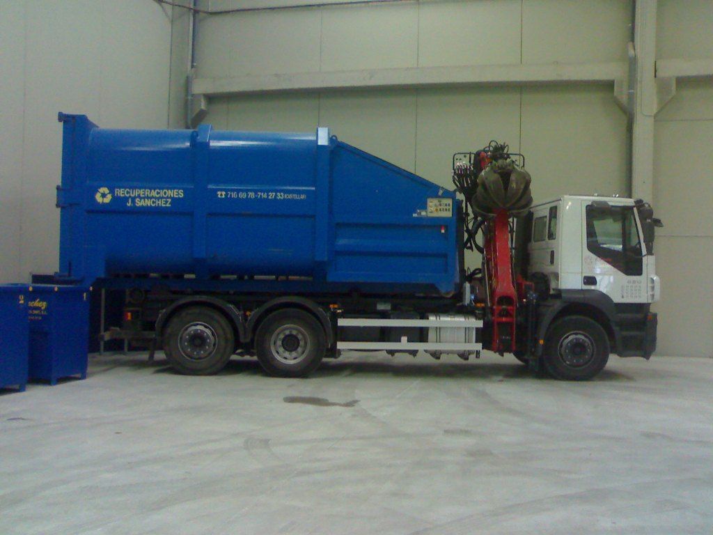 Un camión de basura azul está estacionado en un almacén.