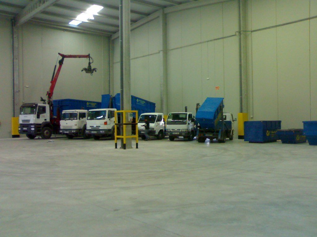 Una fila de camiones están estacionados en un gran almacén.