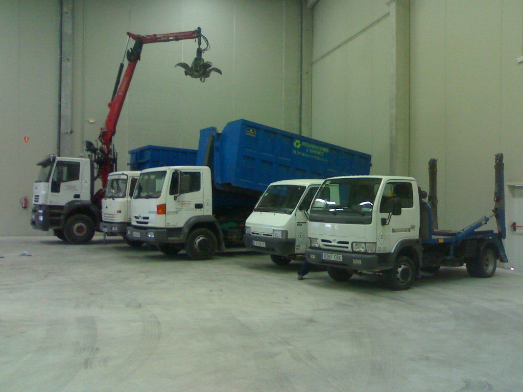 Una fila de camiones de volteo están estacionados en un almacén.