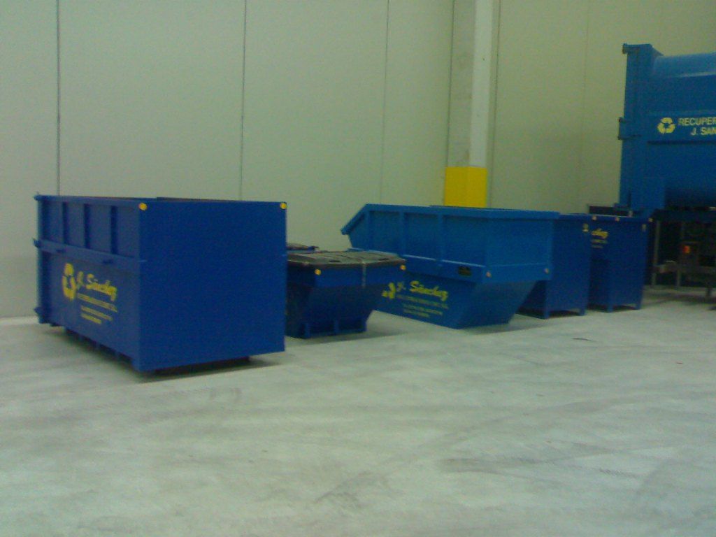 Una fila de contenedores de basura azules con la palabra reciclaje en ellos.