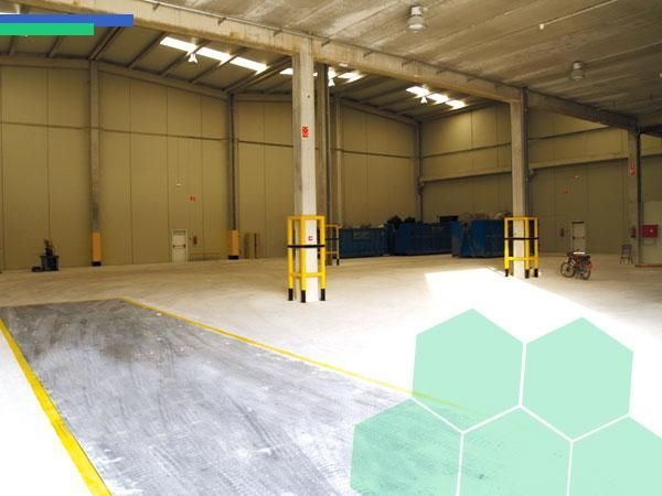 Un almacén vacío con un hexágono verde al fondo.