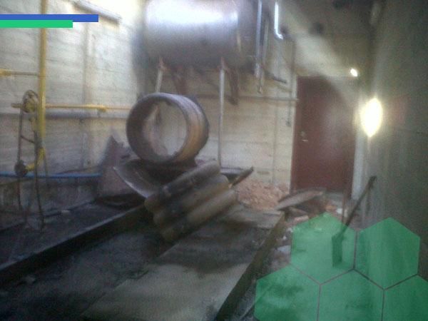 Una habitación con muchas tuberías y una sombrilla verde.