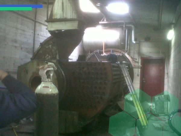 Un hombre sostiene un cilindro de gas delante de una máquina.