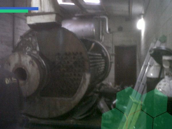 Una máquina grande en una habitación con un cubo verde en primer plano.