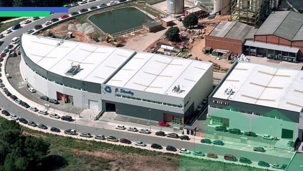 Una vista aérea de un gran edificio con muchos autos estacionados frente a él.