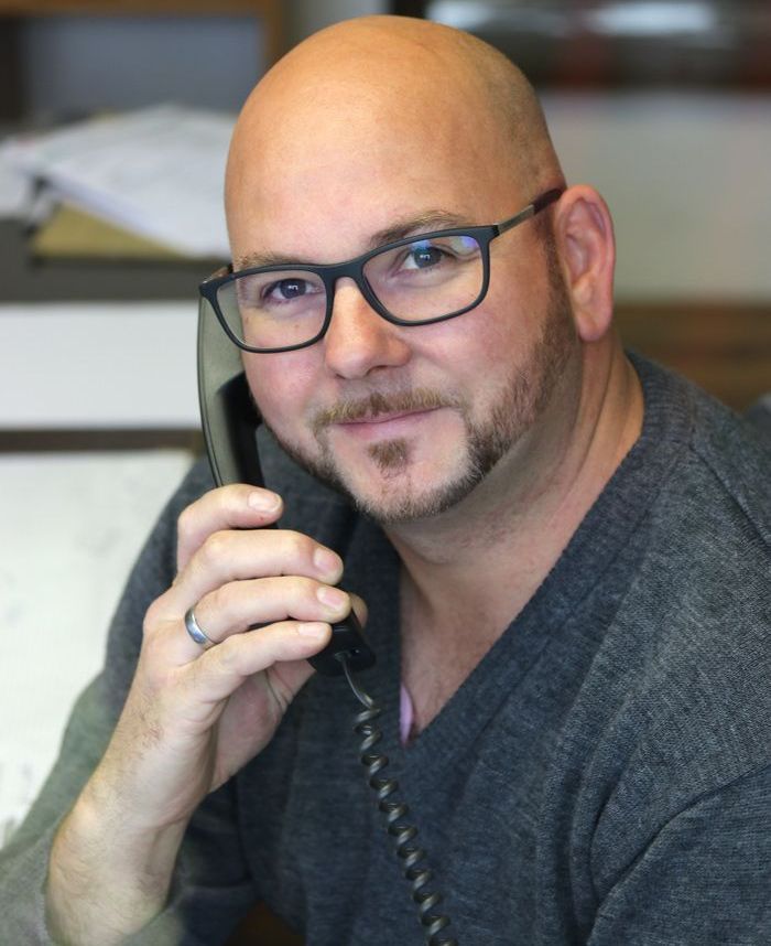 Ein Mann mit Brille und Bart telefoniert