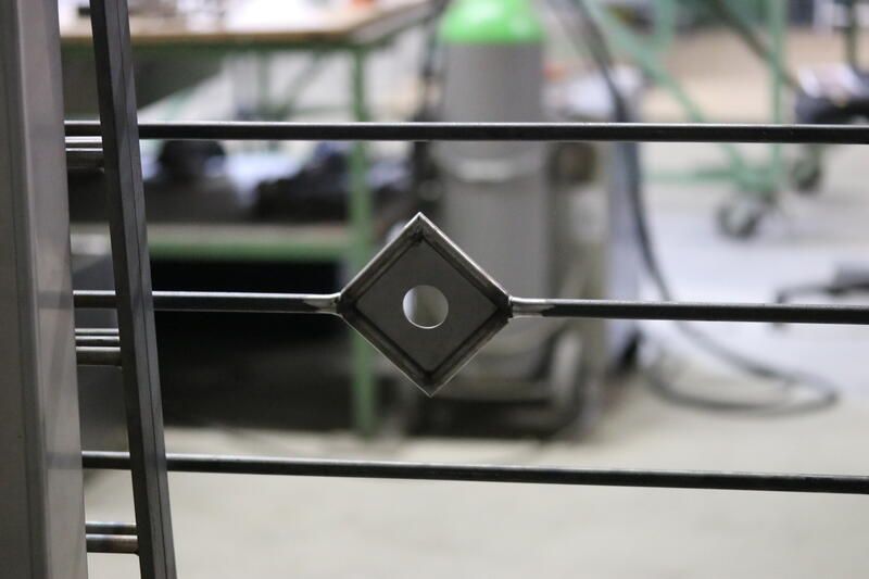 Eine Nahaufnahme eines Metallzauns mit einem Rautenmuster darauf.