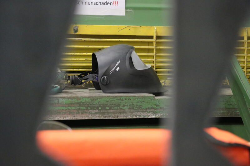 In einer Fabrik liegt ein Schweißhelm auf einem Tisch.