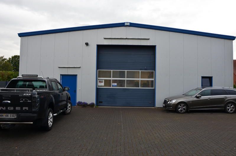 Zwei Autos parken vor einem weißen Gebäude mit einem blauen Garagentor.