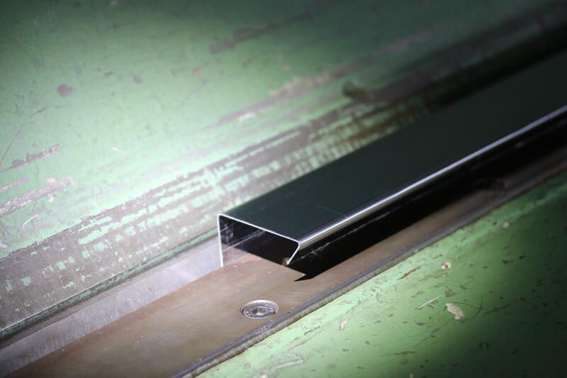 Auf einem grünen Tisch liegt eine Metallstange.