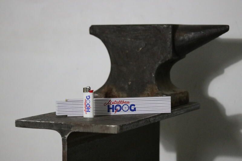 Auf einem Metallträger neben einem Amboss liegt ein Feuerzeug.