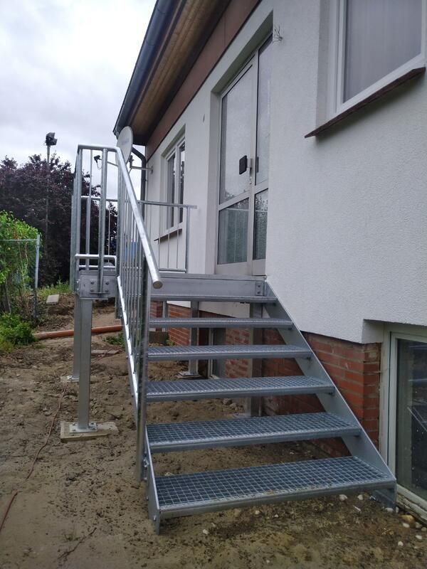 Eine Metalltreppe führt zu einem weißen Haus hinauf.