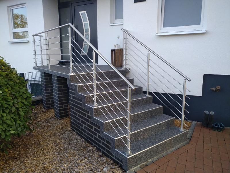 Eine Treppe mit einem Edelstahlgeländer vor einem Haus.