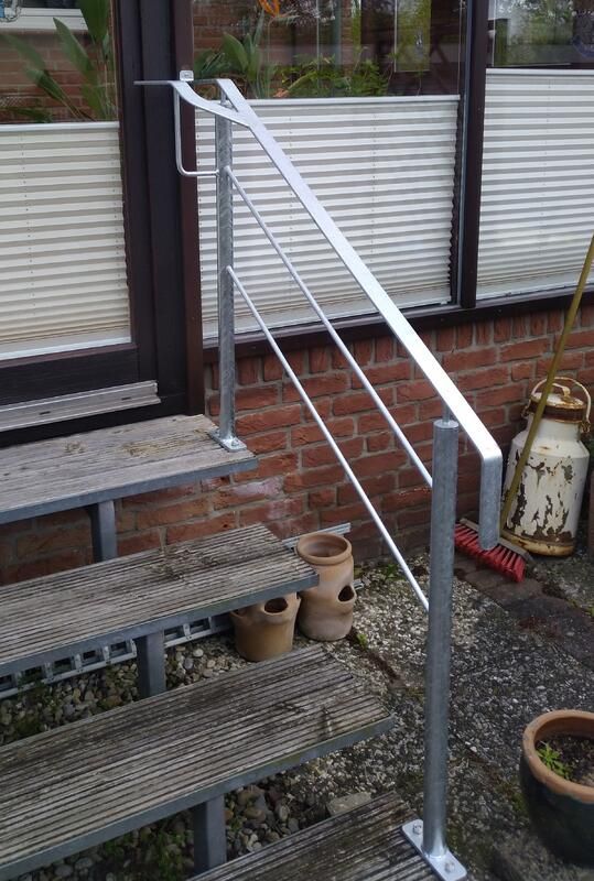 An einer Holztreppe ist ein Metallgeländer befestigt.