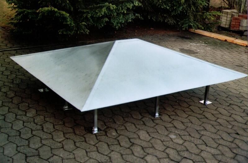 Ein Schornsteinschutz liegt auf einem Ziegelsteinpflaster.