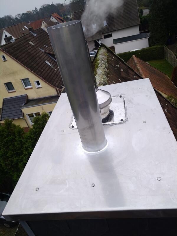 Ein Schornstein auf einem Dach, aus dem Rauch aufsteigt