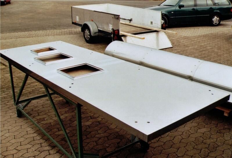 Ein Anhänger ist hinter einem großen Metalltisch geparkt