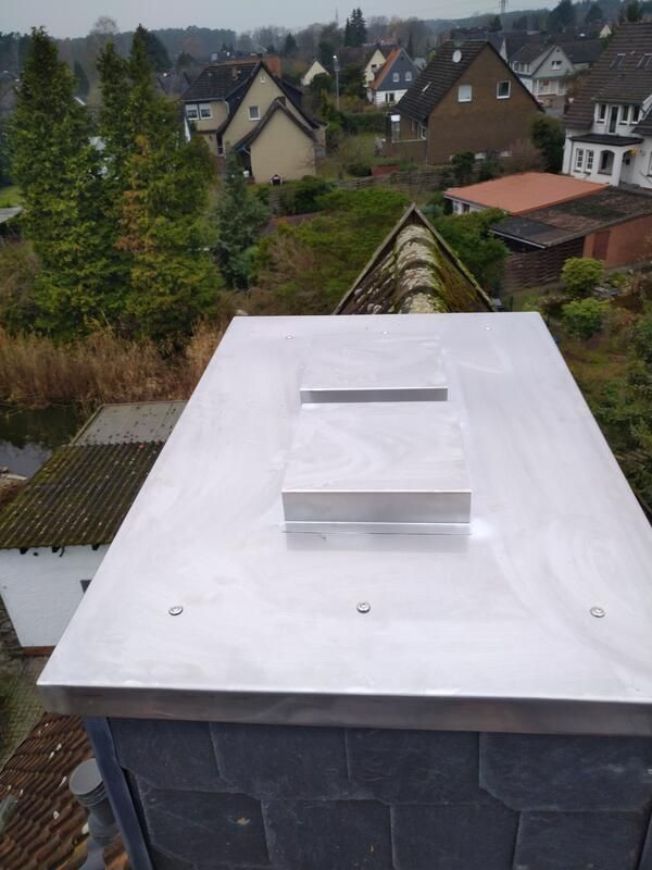 Ein Schornsteinschutz mit einer Edelstahlabdeckung darüber.