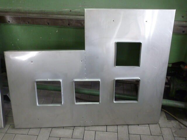 Auf einem gefliesten Boden liegt ein Stück Aluminium mit drei quadratischen Löchern.