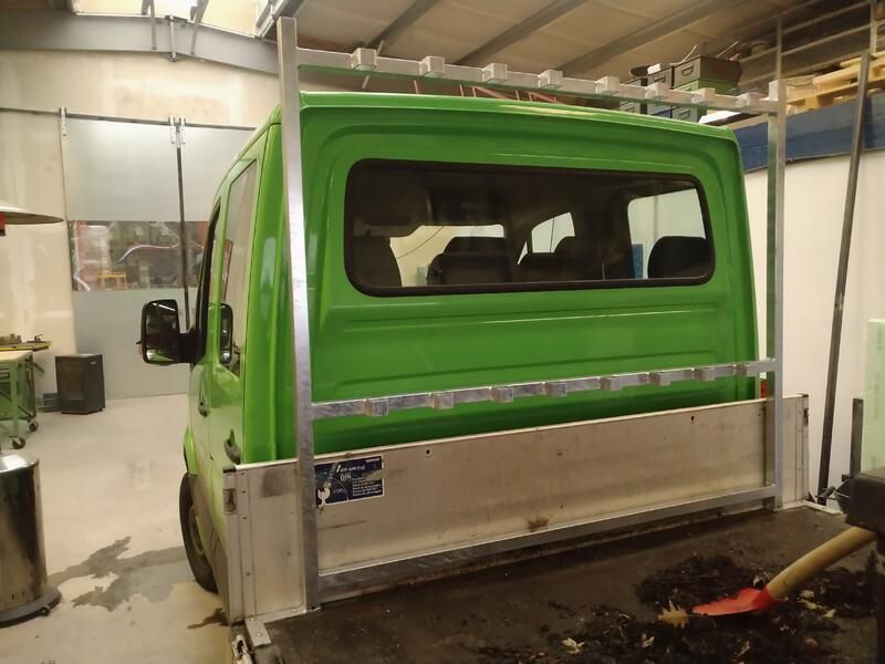 Ein grüner Lieferwagen steht in einer Garage.