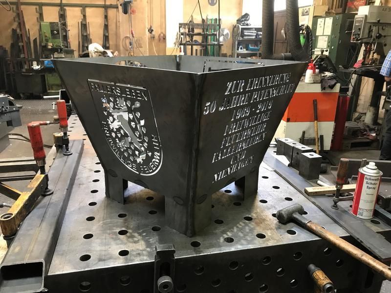 In einer Fabrik liegt ein großes Metallobjekt auf einem Tisch.