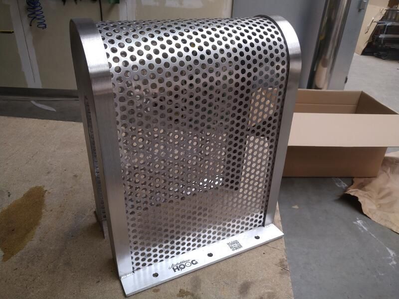 Ein Edelstahlgegenstand mit Löchern darin liegt neben einem Karton