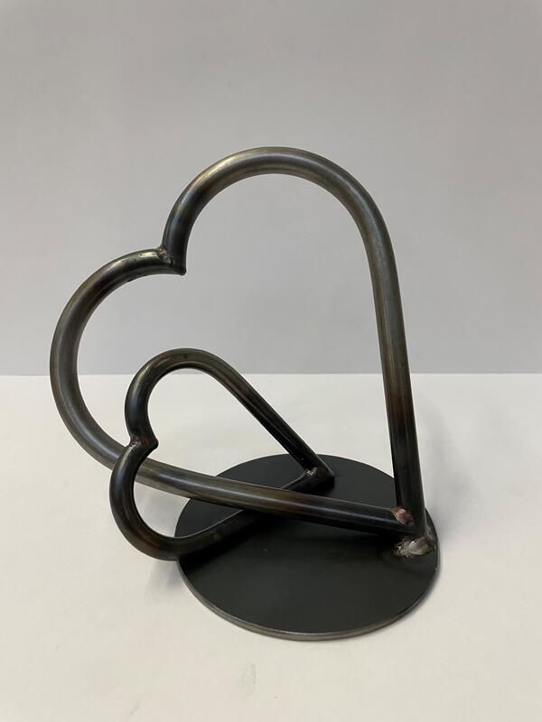 Eine Metallskulptur zweier Herzen auf einem weißen Tisch.