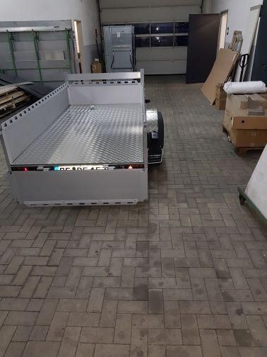 In einer Garage neben einem Ziegelboden ist ein Anhänger geparkt.