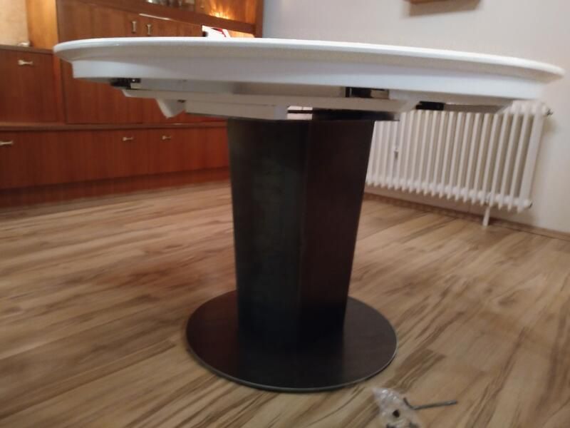 Ein weißer Tisch mit schwarzem Untergestell steht auf einem Holzboden