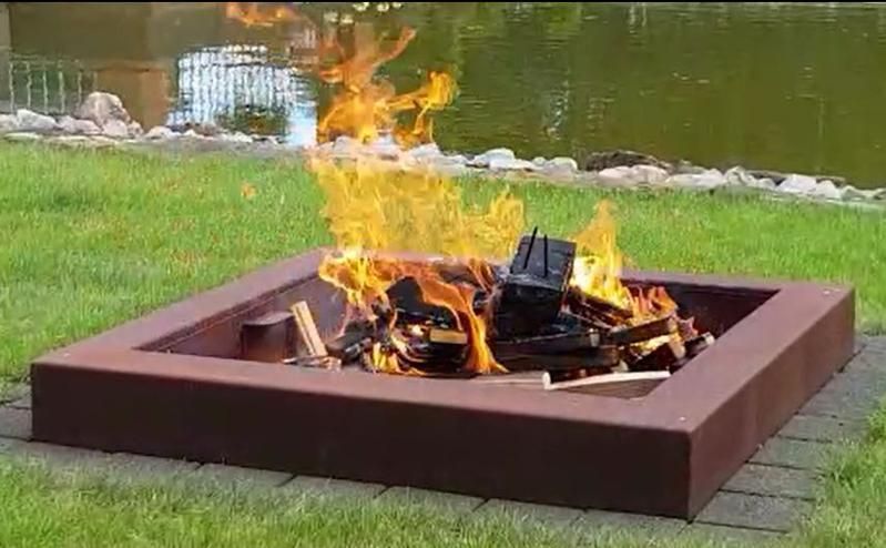 Im Gras neben einem Gewässer steht eine Feuerstelle.