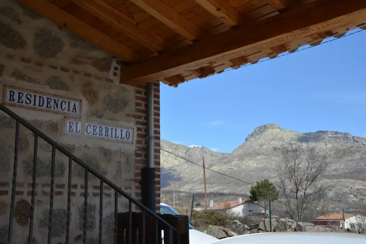 Porche de una casa de piedra con vistas a las montañas bajo un cielo azul despejado.