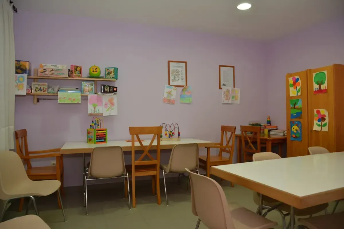 Sala de juegos tranquila para niños con mesas, sillas, estantes de pared y coloridos armarios de almacenamiento.